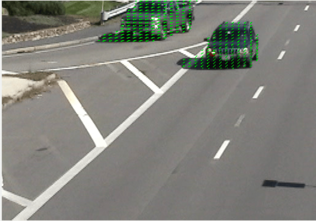 Cars traveling on a highway with overlaid optical flow vectors.